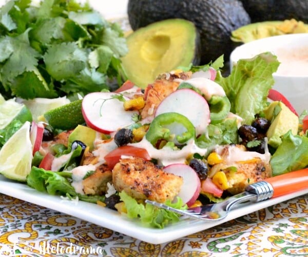 loaded southwest chicken salad with roasted corn and black beans over fresh greens