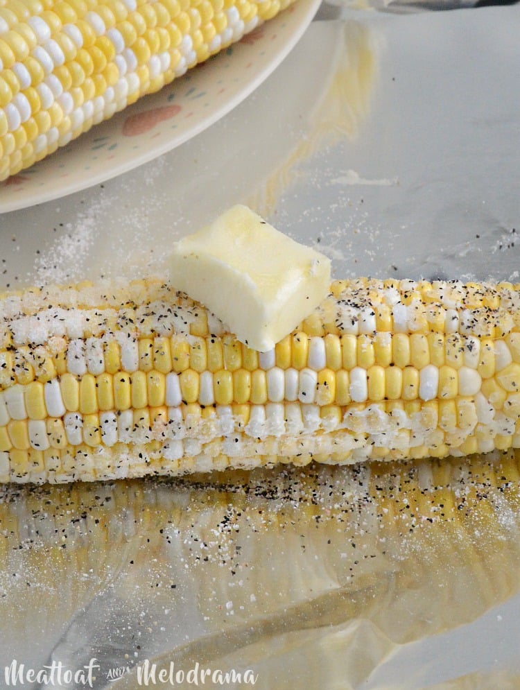 butter salt and pepper on fresh corn wrapped in aluminum foil