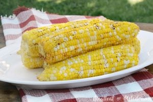 foil grilled corn on the cob on platter in backyard