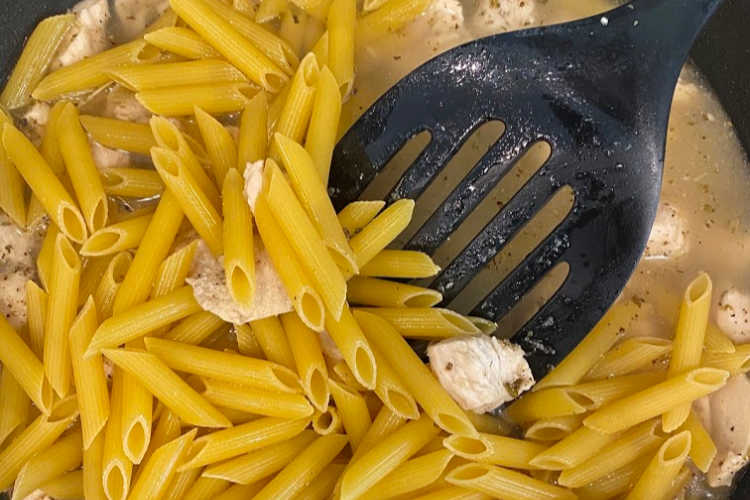 penne pasta, water and chicken in skillet
