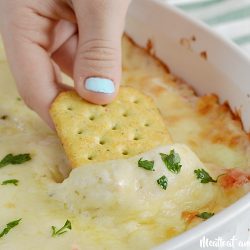 cheesy hot crab dip with melted cheese on cracker