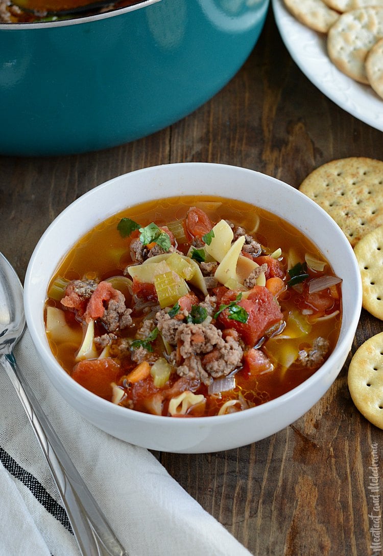 ground beef noodle soup with tomatoes and carrots in white bowl