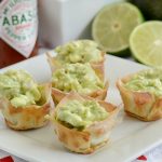 avocado dip wonton cups on a platter with tabasco sauce