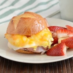 cheesy ham and egg breakfast sliders on plate with fruit