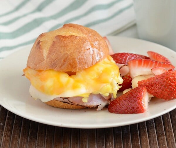 cheesy ham and egg breakfast sliders on plate with fruit