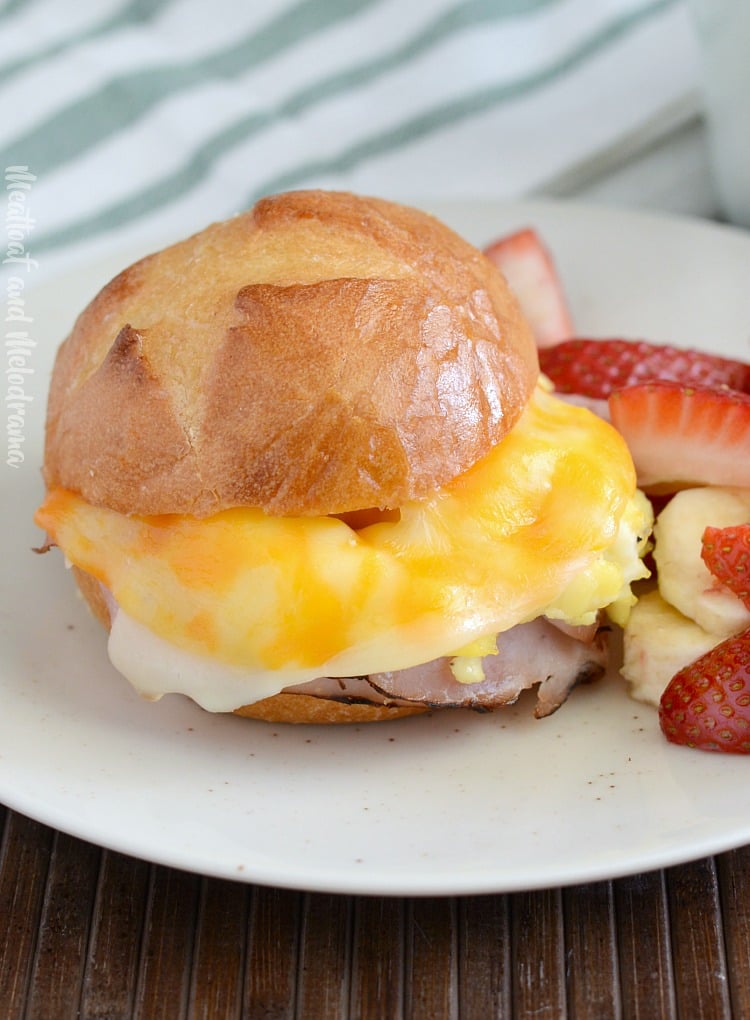 cheesy ham and egg breakfast sliders on plate with strawberries