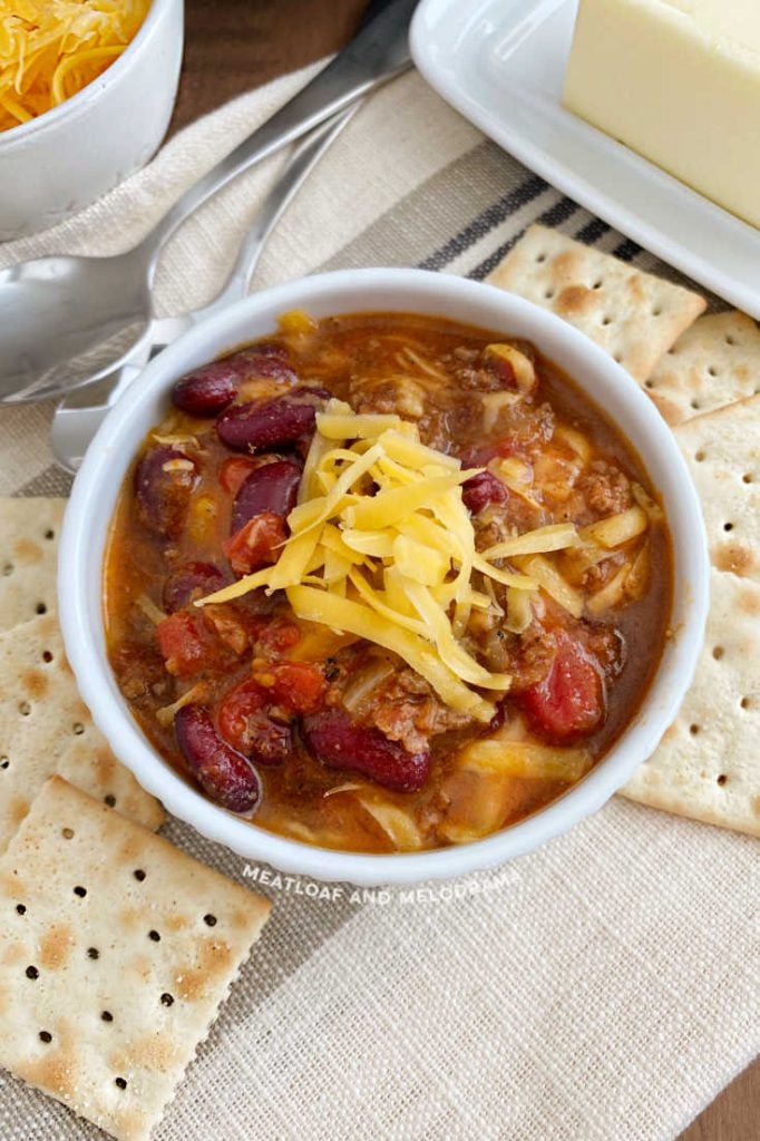 ground beef and bean chili in a white bowl with crackers