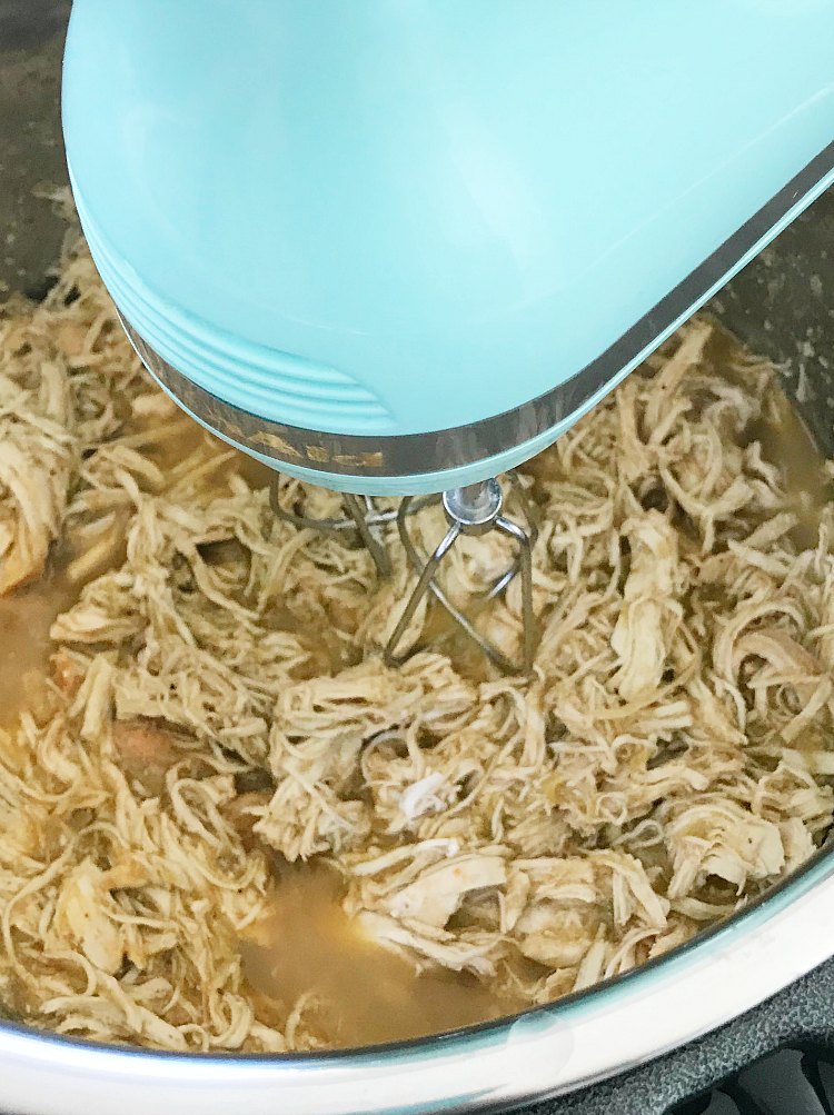 Shred salsa verde chicken with electric mixer in pressure cooker