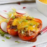 leftover chili stuffed peppers with cheddar cheese on a plate with lettuce and radishes