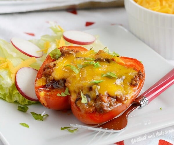 leftover chili stuffed peppers with cheddar cheese on a plate with lettuce and radishes