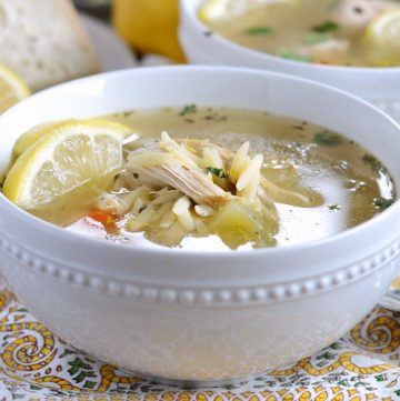 instant pot lemon chicken orzo soup in a bowl with lemon slices