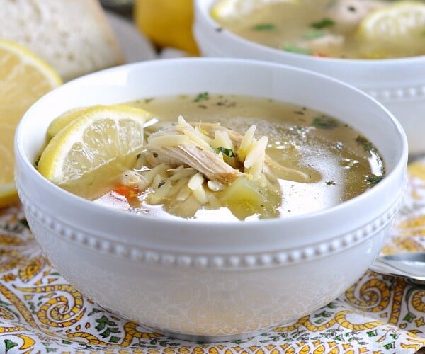 instant pot lemon chicken orzo soup in a bowl with lemon slices