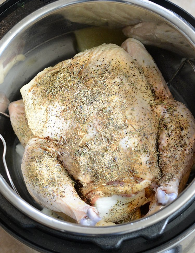 uncooked seasoned whole chicken in pressure cooker pot