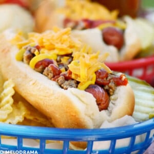 cheeseburger hot dog in blue basket with chips