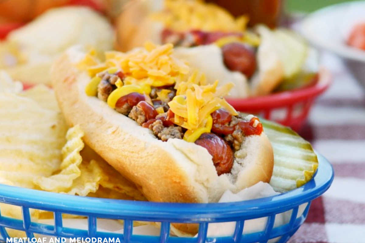 cheeseburger hot dog in blue basket with chips