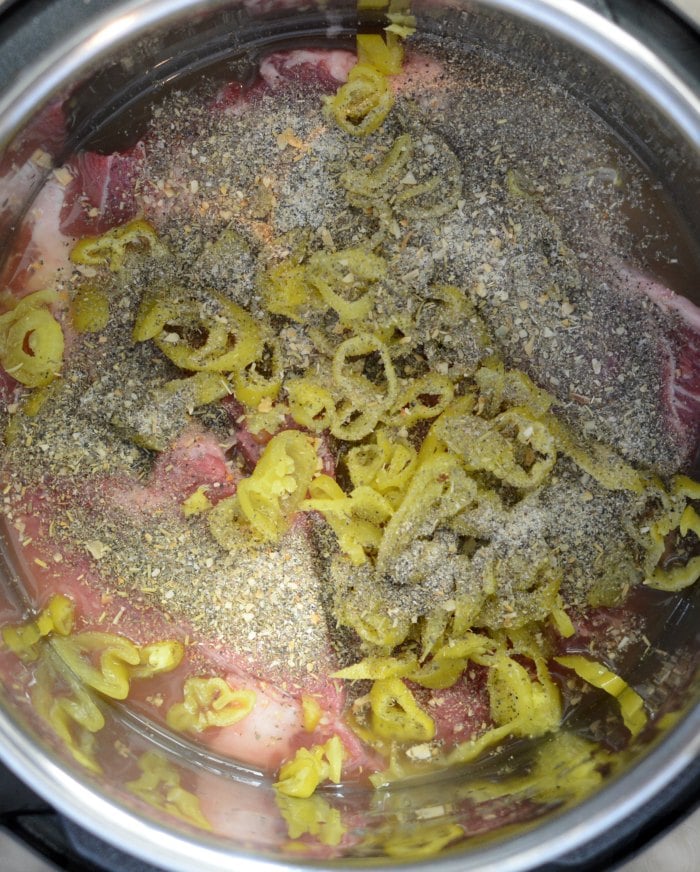 chuck roast with seasoning and pepperoncini in instant pot