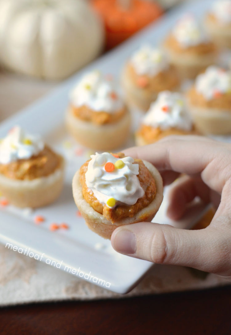 pumpkin cheesecake cookie cups with whipped cream and sprinkles in hand
