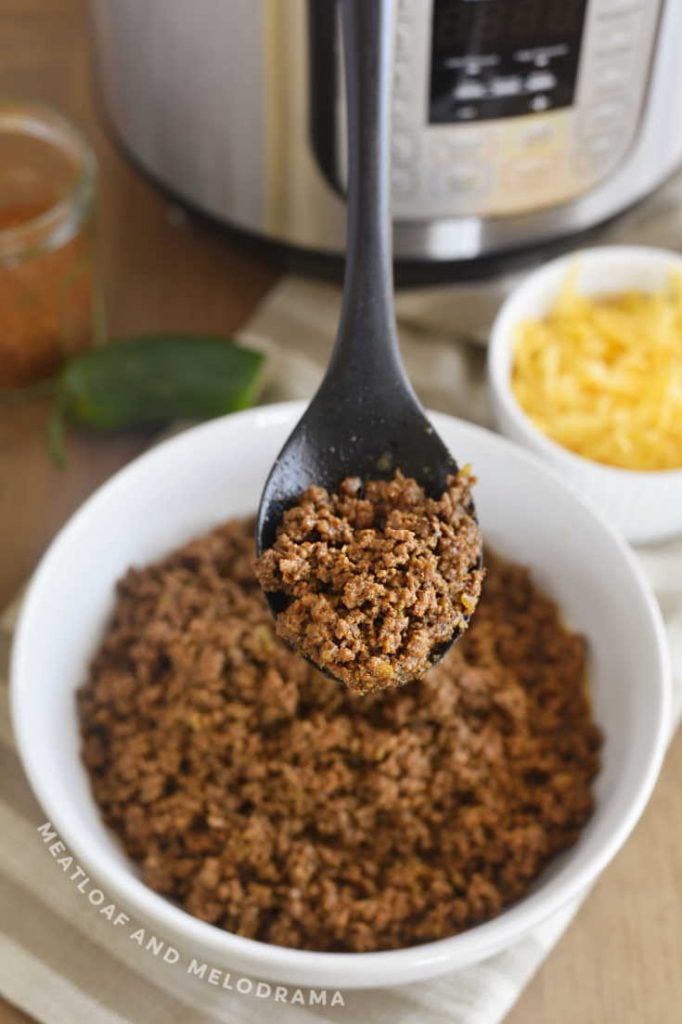 seasoned ground beef taco meat on a serving spoon with instant pot in background