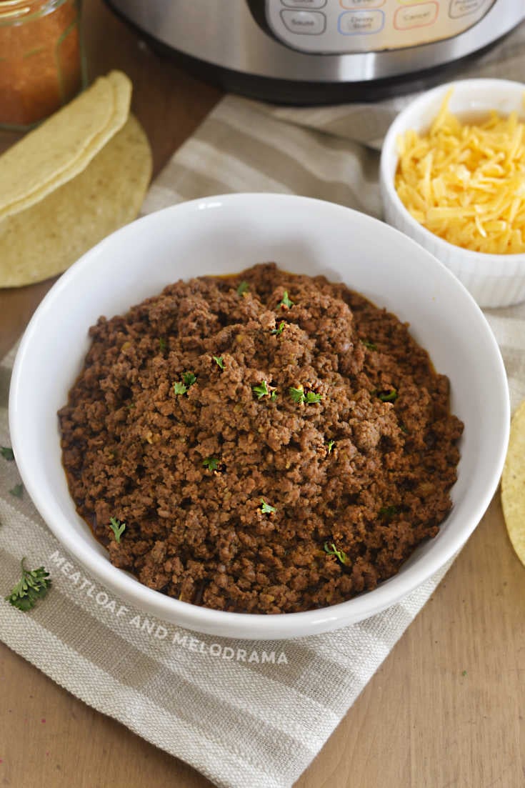bowl of Instant Pot ground beef taco meat on the table with cilantro and cheese
