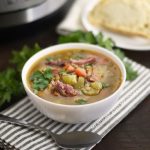instant pot ham and lentil soup in a white bowl with bread