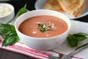 instant pot creamy tomato basil soup with parmesan and basil in a white bowl