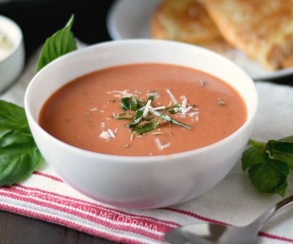 instant pot creamy tomato basil soup with parmesan and basil in a white bowl