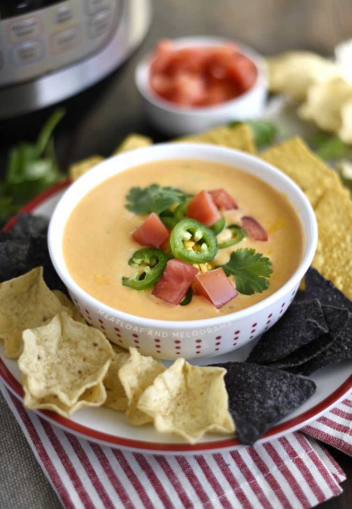 instant pot queso dip recipe in white bowl with tortilla chips and toppings