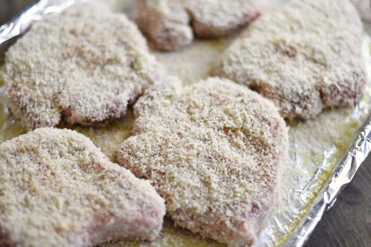 bone in pork chops with panko breading on baking sheet