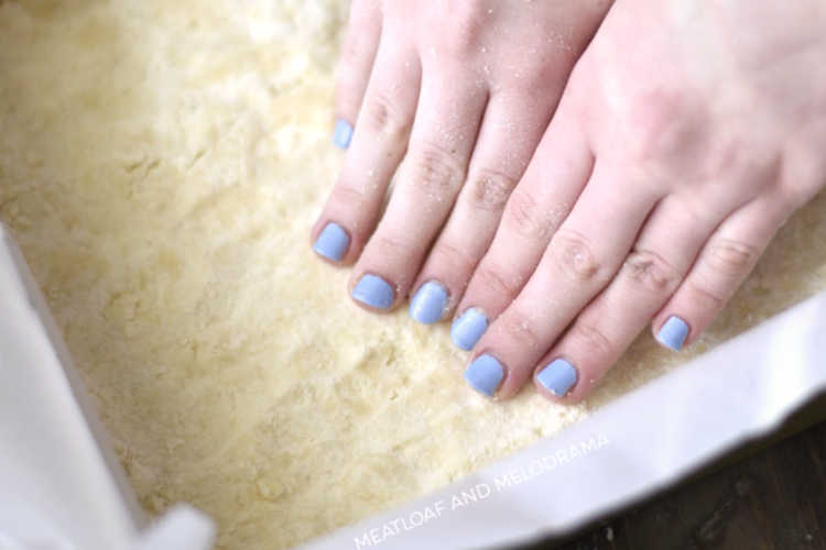 pat shortbread crust in pan with hands