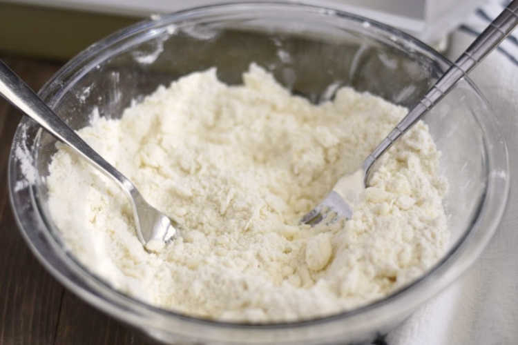 cut flour and butter and sugar for shortbread crust with 2 forks