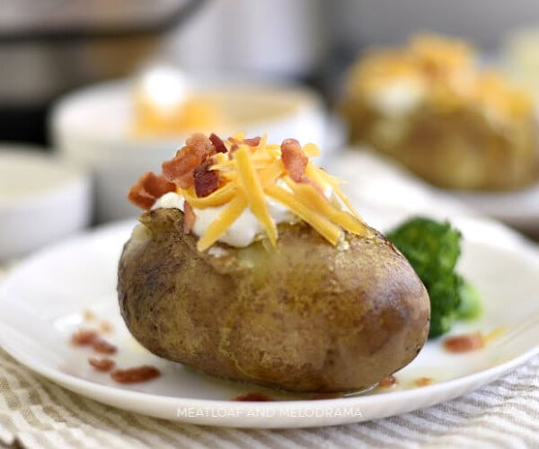 instant pot baked potatoes with sour cream cheddar cheese and bacon on a plate