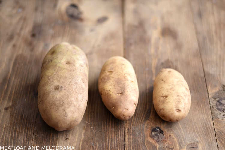 large medium and small russet potatoes on a wood board