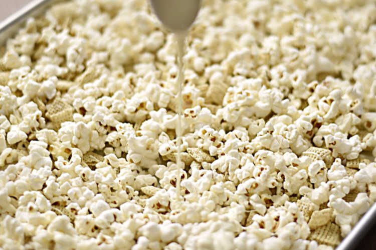 besprenkel witte chocolade over popcorn en chexmix