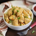 instant pot orange chicken in a white bowl over rice with scallions