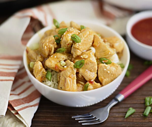 instant pot orange chicken in a white bowl over rice with scallions