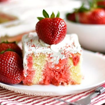 strawberry jello poke cake with strawberries on a white plate