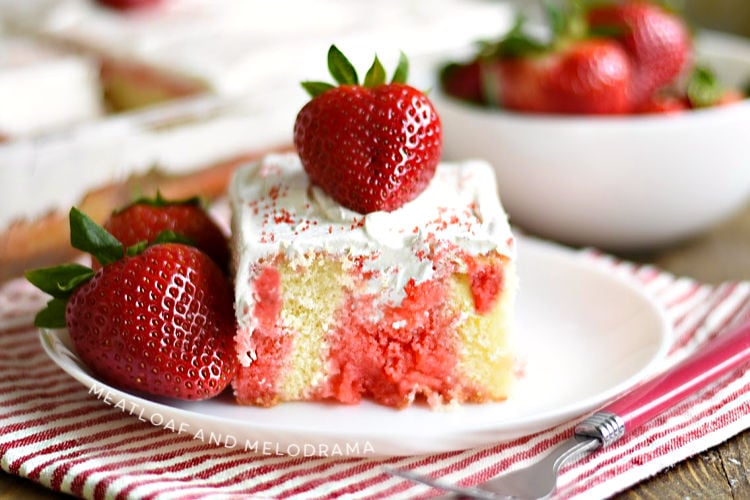 strawberry jello poke cake with strawberries on a white plate