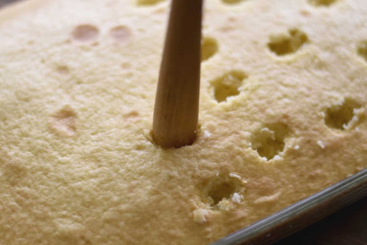 poke holes in cake with wooden spoon