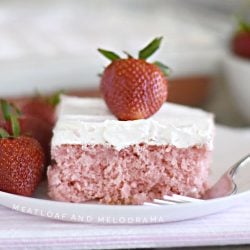 strawberry cream soda cake with whipped topping and strawberry on white plate