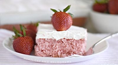 strawberry cream soda cake with whipped topping and strawberry on white plate