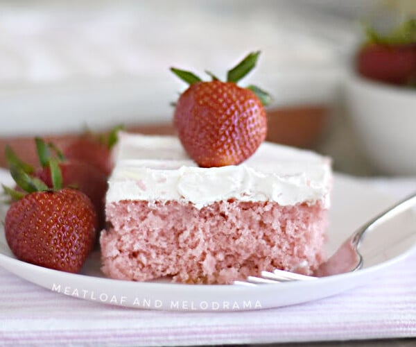 strawberry cream soda cake with whipped topping and strawberry on white plate