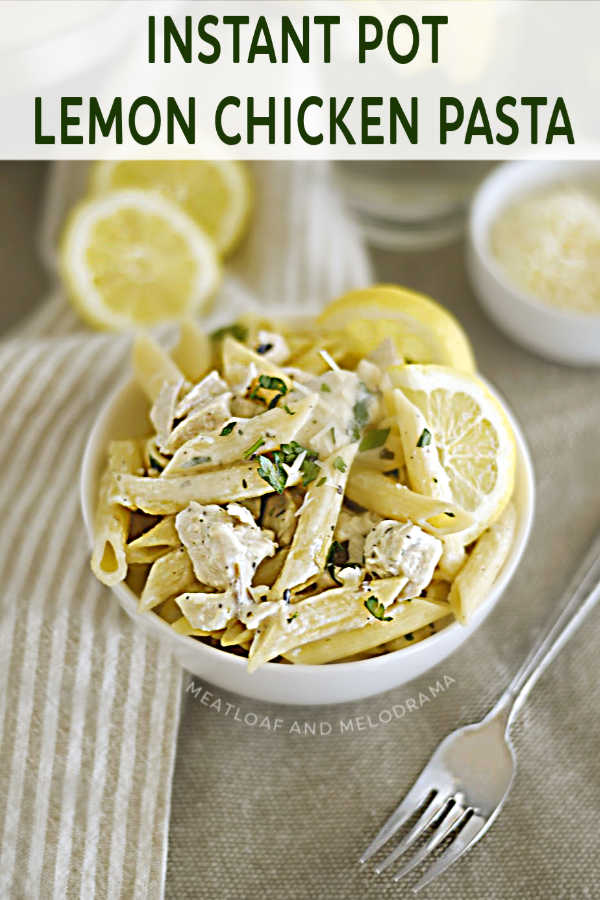Bowl of Instant Pot creamy lemon chicken pasta with parsley and lemon slices and parmesan cheese on tablec 