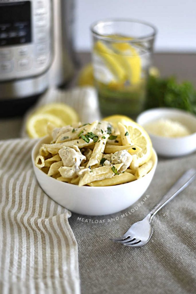 instant pot lemon chicken pasta in a white bowl with parsley and lemon slices