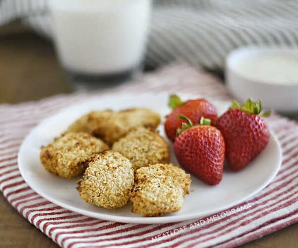 air fryer chicken nuggets with panko breadcrumbs and strawberries on a white plate