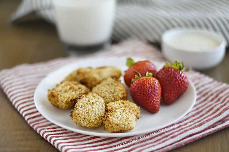 air fryer chicken nuggets with panko breadcrumbs and strawberries on a white plate