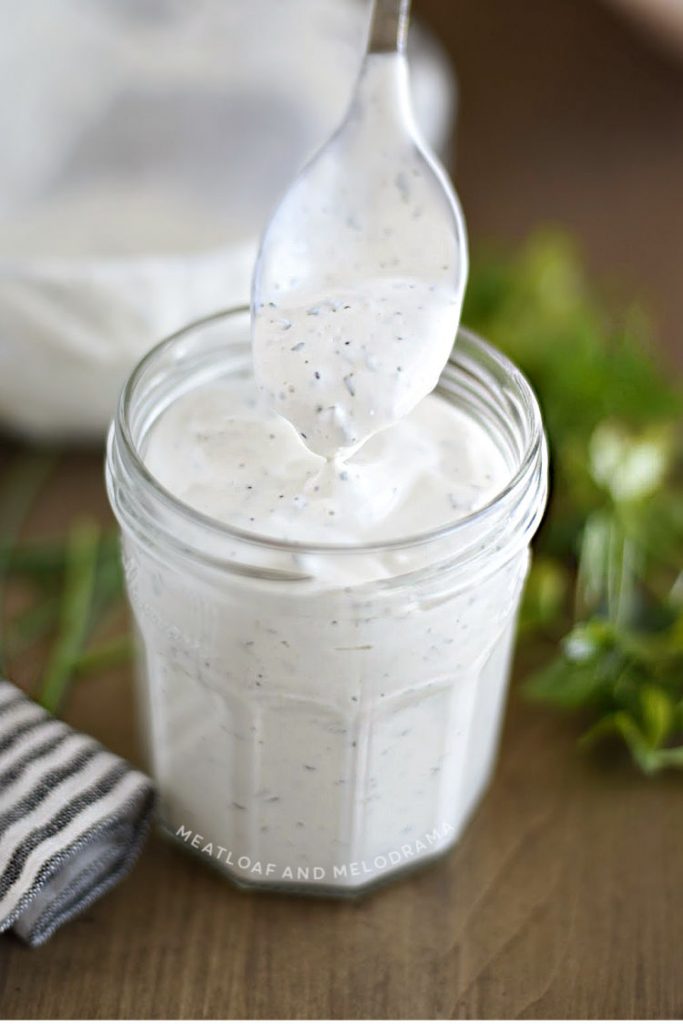 spoon dipping into jar of homemade ranch dressing 