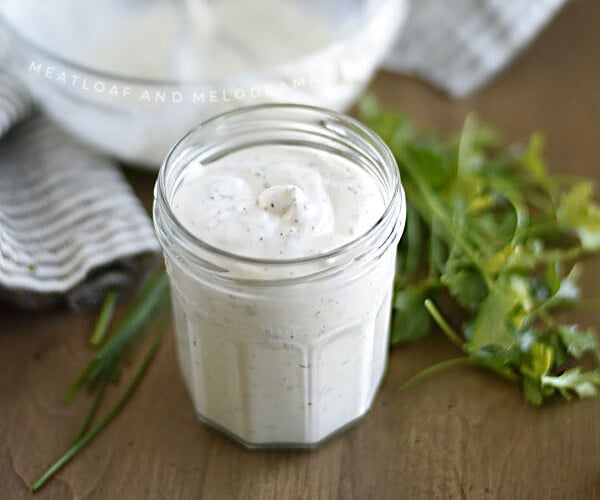 homemade ranch dressing in a glass jar with parsley and chives