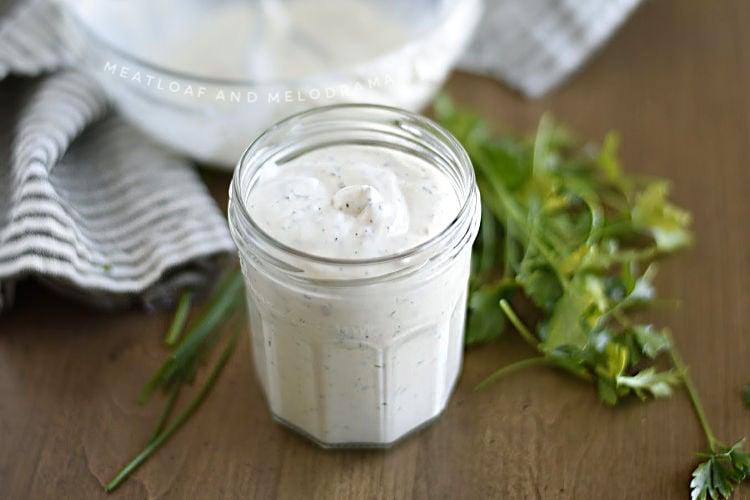 homemade ranch dressing in a glass jar with parsley and chives