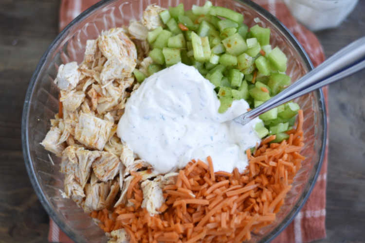 mix ranch dressing with buffalo chicken, carrots and celery in bowl
