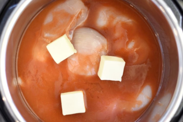 chicken breasts with buffalo sauce and butter in electric pressure cooker